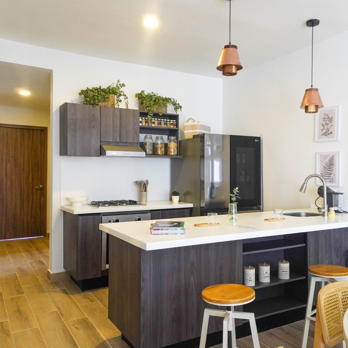 Cocina integral con isla, refrigerador y lámparas colgantes de cobre