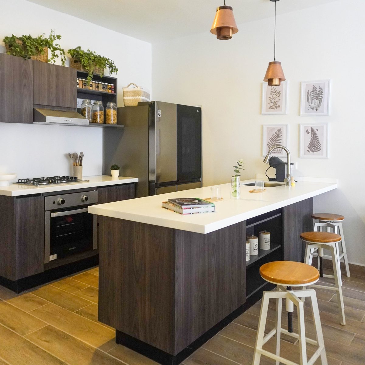 Cocina integral con isla, bancos y lámparas colgantes de cobre