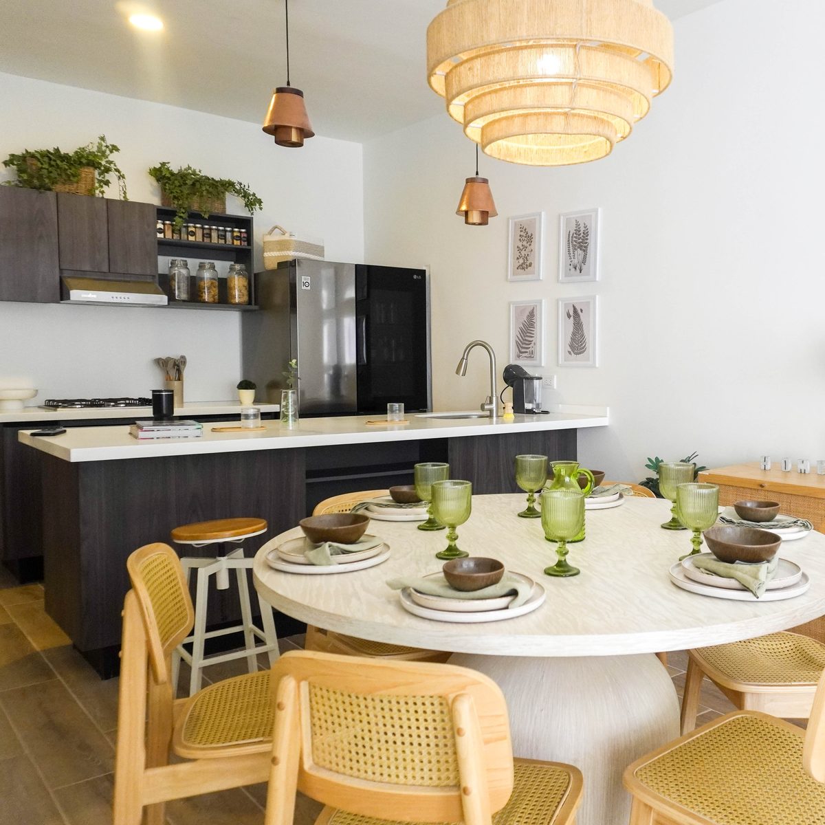 Comedor redondo con la mesa puesta y cocina integral con isla al fondo