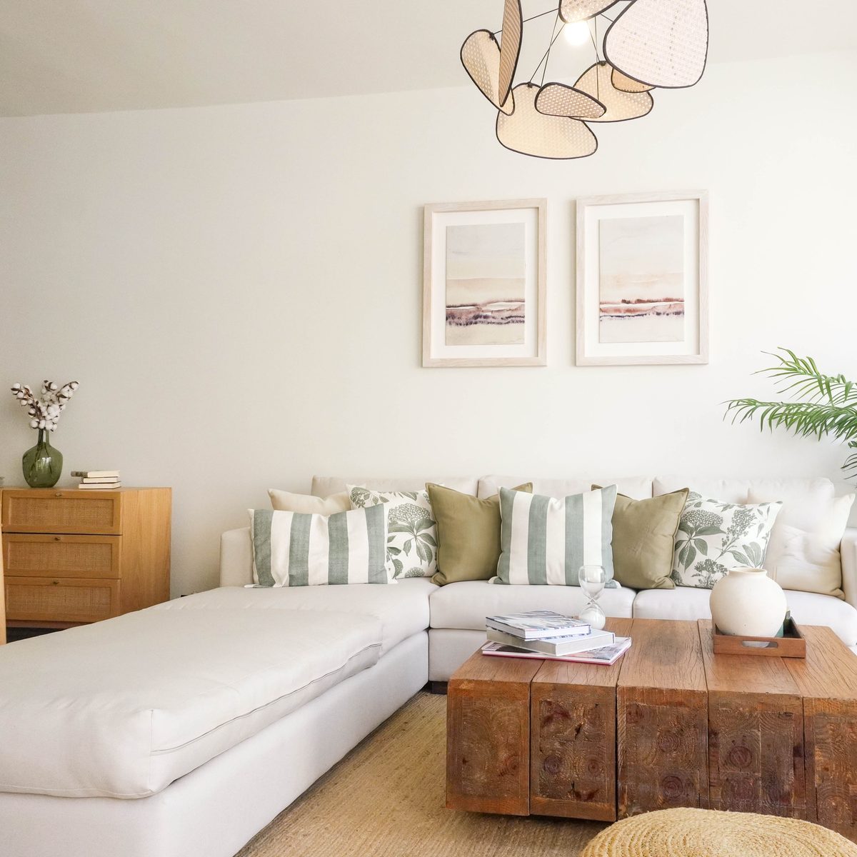 Sala con sofá en L, dos cuadros y lámpara colgante